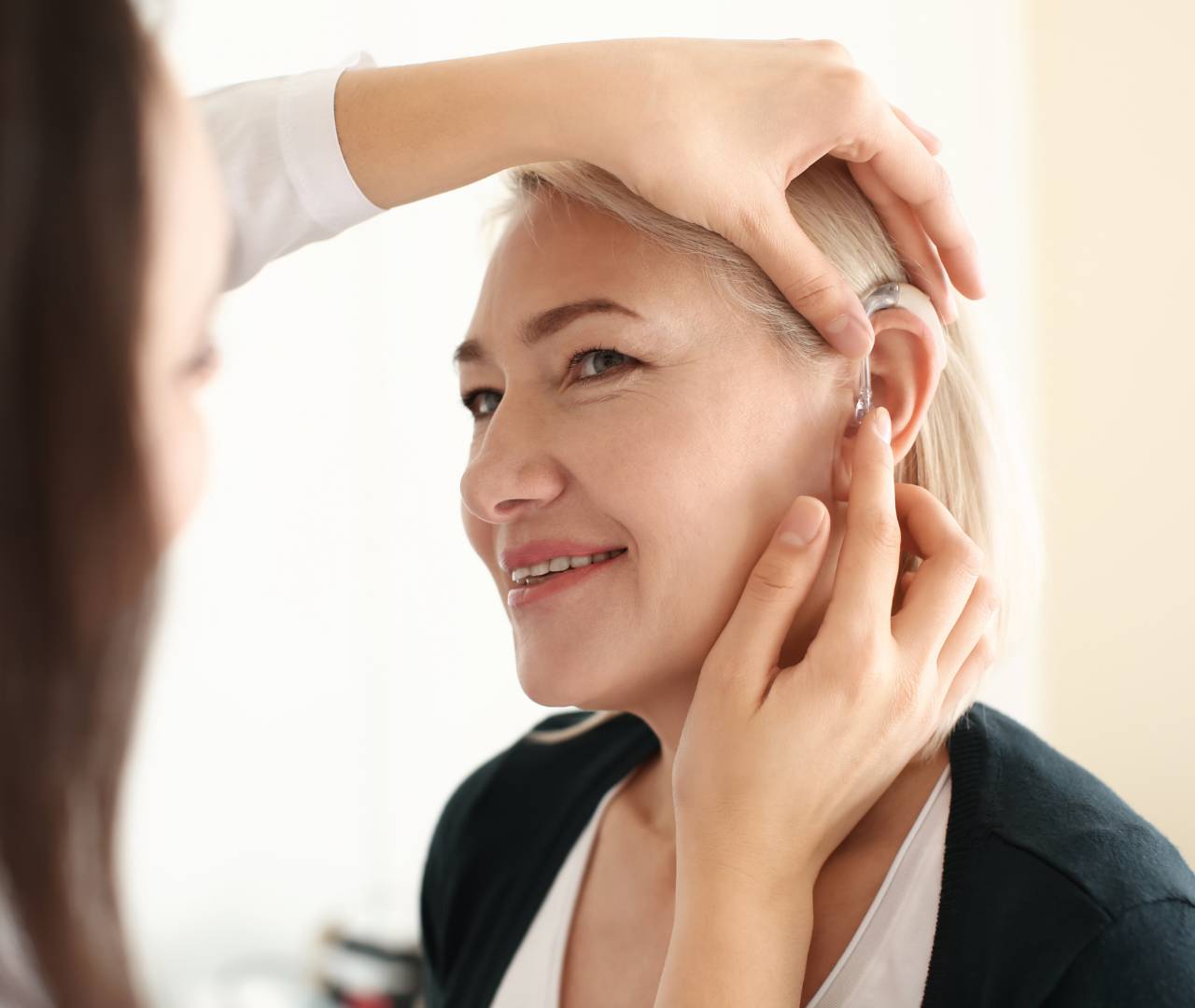 Hearing care professional putting hearing aid in woman's ear