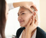 Hearing care professional putting hearing aid in woman's ear