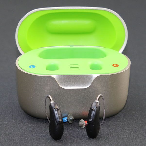 Charging case with neon green inside and hearing aids sitting in front of the case