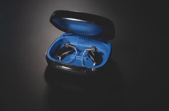 Pair of hearing aids in a blue case on a black background