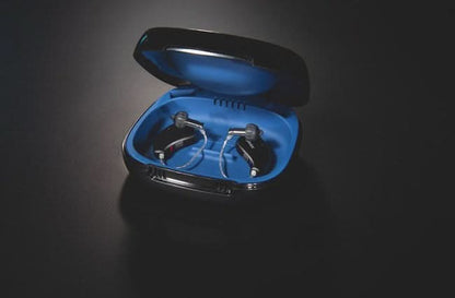 Pair of hearing aids in a blue case on a black background