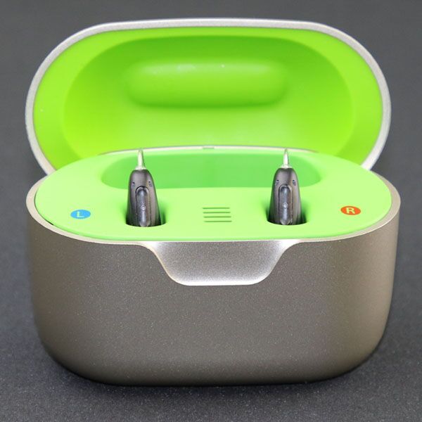 Charging case with neon green inside and hearing aids inserted