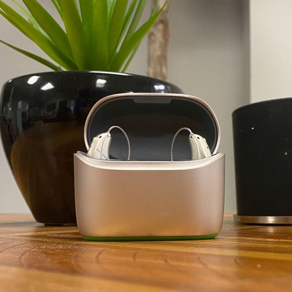 Charging case with hearing aids inside sitting on a wooden table